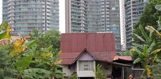 A traditional Malay house in Kampong Bharu, overshadowed by high-rise apartment towers