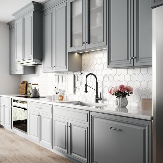 All grey kitchen cabinets with white hexagonal backsplash and white countertop