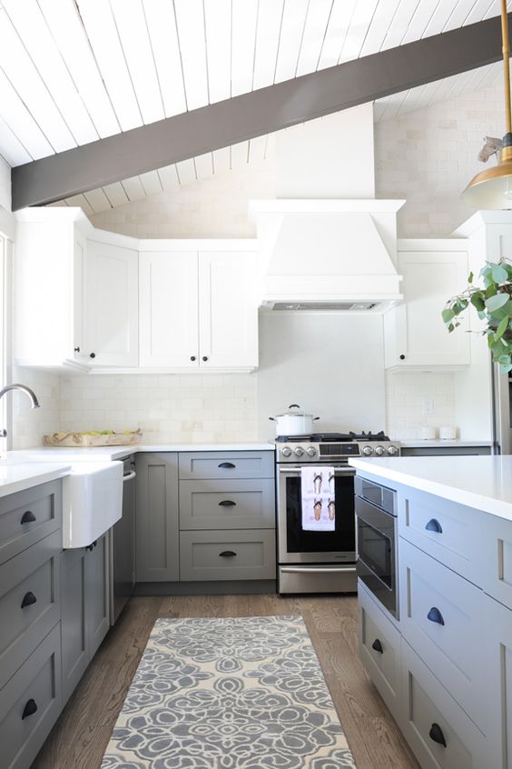 White kitchen cabinets on top with gray cabinets on the bottom and stainless steel appliances