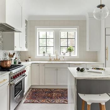 Pretty little white kitchen with marble countertop and gold accents and plenty of natural light