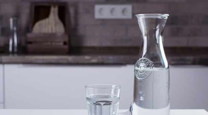 Glass of pure water and bottle on kitchen table. Clean Concept