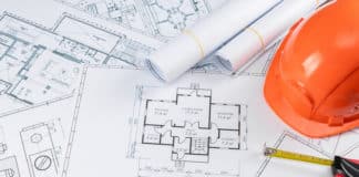 Orange helmet, pencil, architectural construction drawings, tape measure. The concept of architecture, construction, engineering, design. Copy space.
