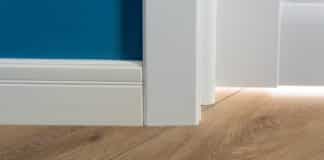 Laminated parquet floors immitating oak texture, white baseboard