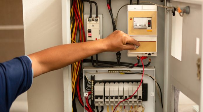Senior electrician measuring voltage in fuse board