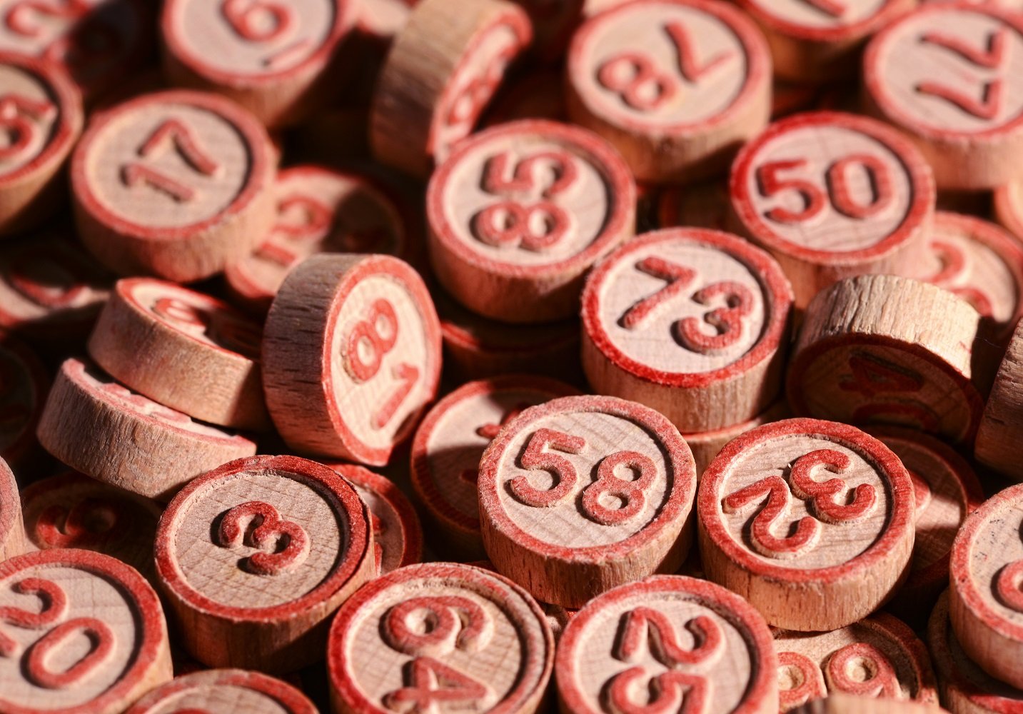 Background of lucky bingo numbers on round wooden tokens to be drawn at random during the game and marked off on the bingo cards for a win