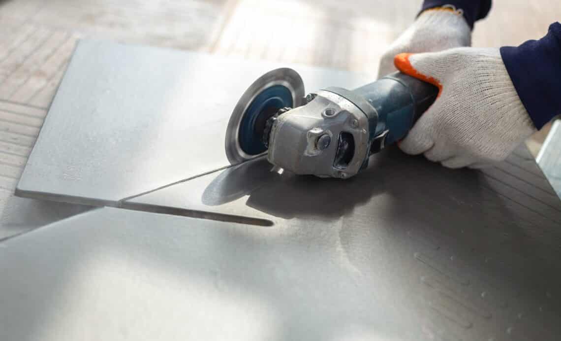 Worker cutting a tile using an angle grinder at construction site
