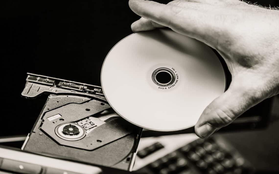 Male hand inserting a dvd into a disk drive. Black and white.