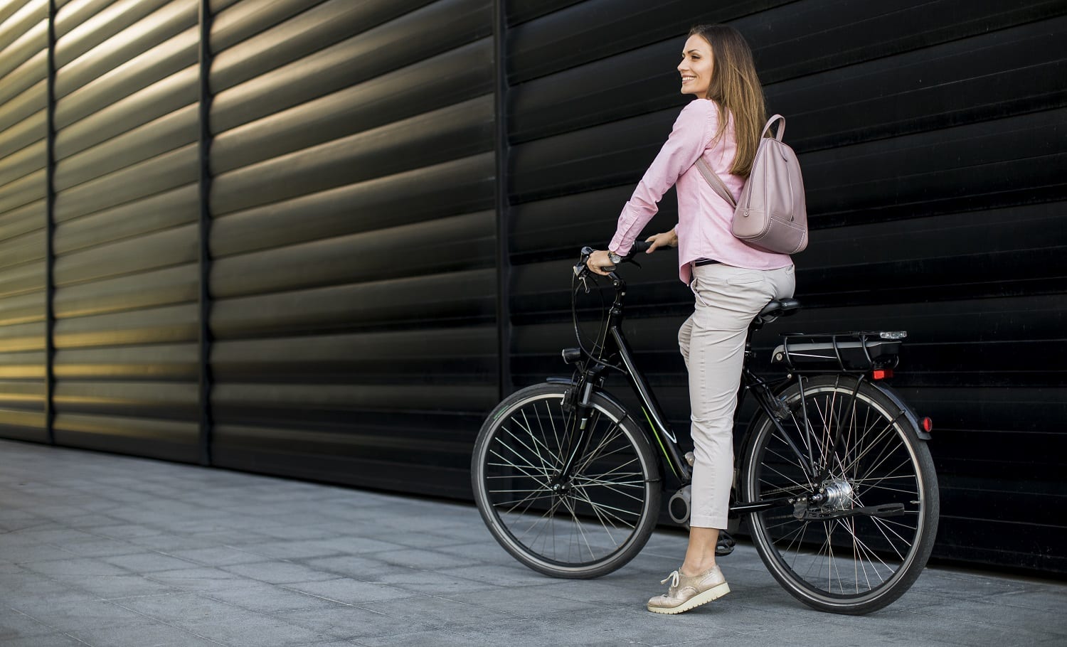 Pretty young woman riding an electric bicycle in urban environment