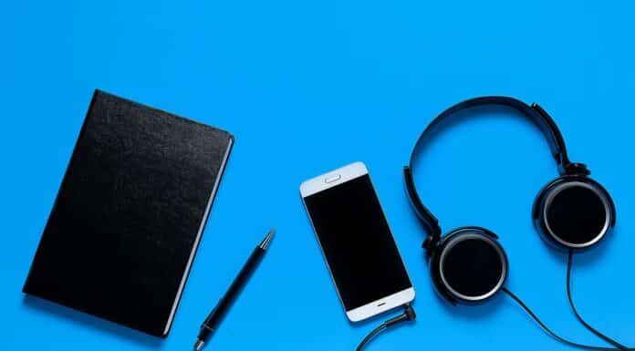 Mobile Phone, Headphones, Notepad And Pen On A Blue Background