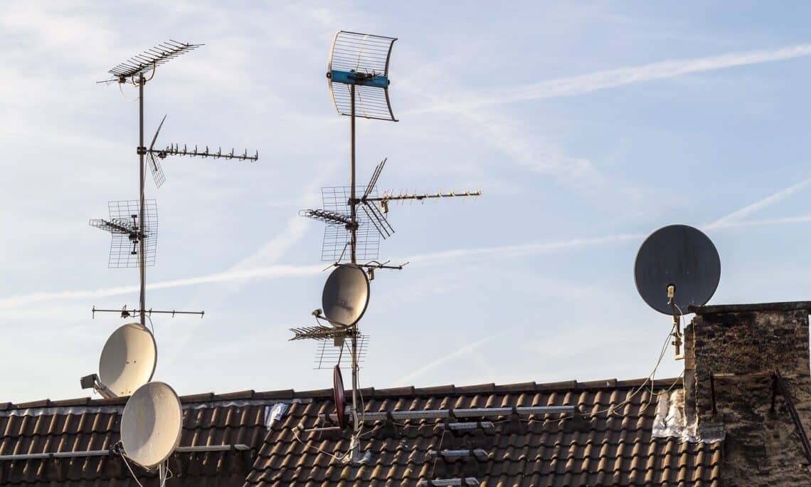 Old building roof with many different type receiver telecommunication antennas