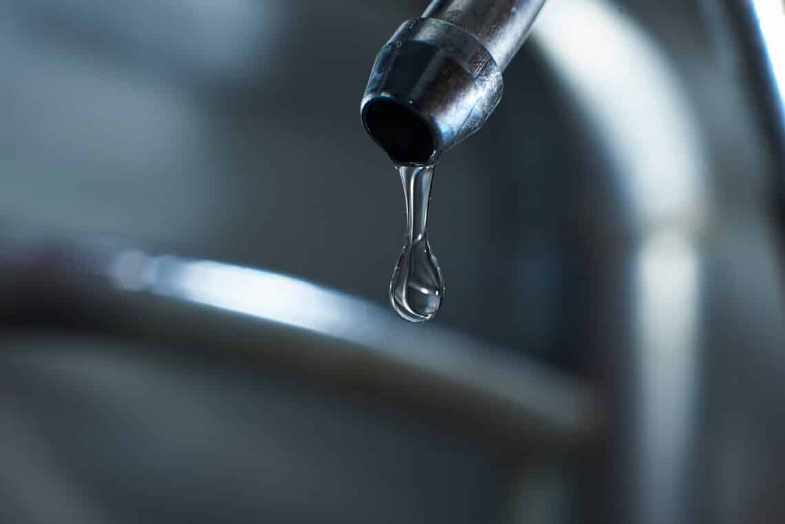 Reverse osmosis filter tap closeup with dripping water-drop. Studio shot.