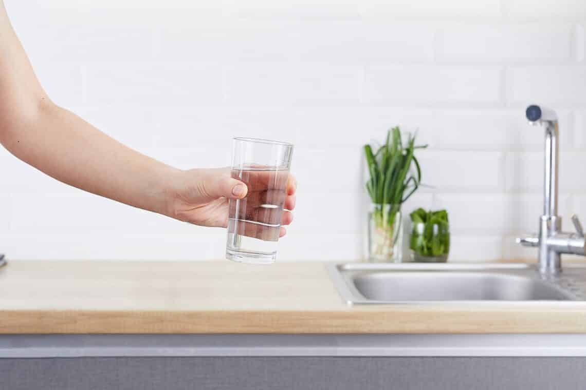 Female hand holding a glass of clean water. Purified water and a healthy life concept.
