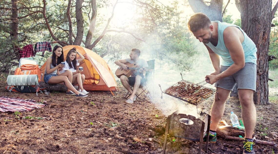 Party, camping of men and women group at forest. They relaxing, singing a song and cooking barbecue against green grass. The vacation, summer, adventure, lifestyle, picnic concept