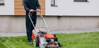 Man cutting grass with lawn mover in the back yard