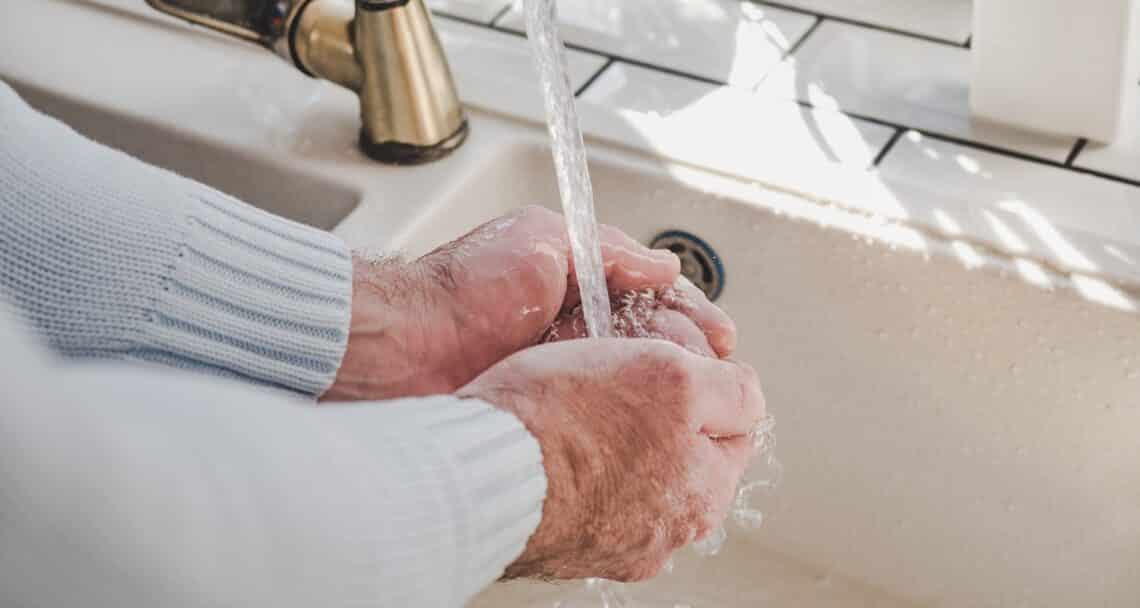 Men's hands and a bar of soap on a background of a vintage tap. Top view, closeup. Health care and prevention concept