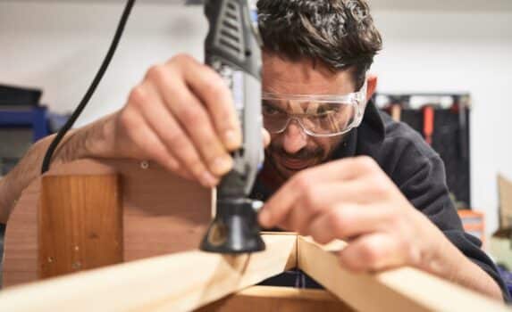 Portrait of young man with safety glasses working with a dremel tool