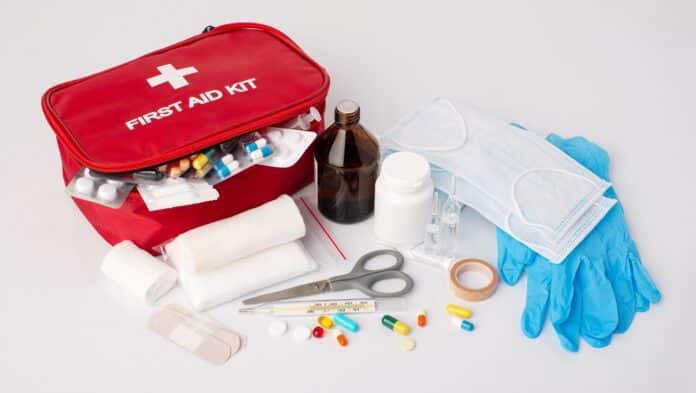 First aid kit on white table. Full set of emergency medicine, medication for giving first aid to a sick or injured person on white background