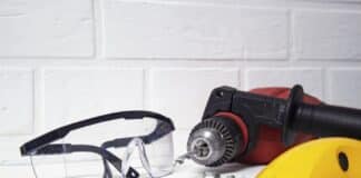 Professional tool for drilling. Electric drill with safety glasses on a brick wall background