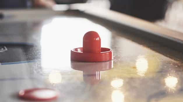 Air hockey table with window lighting and red toy hockey stick.