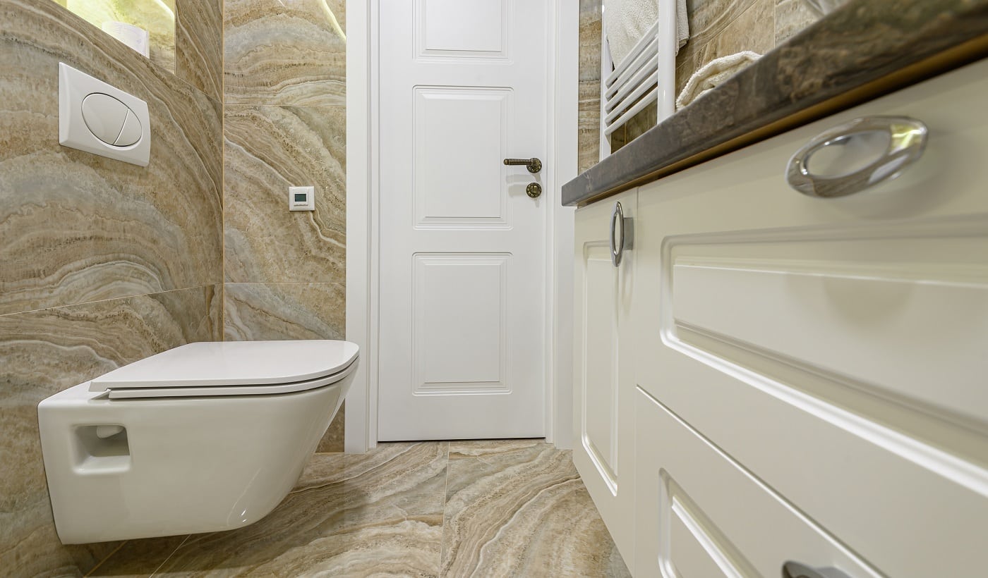 Spacous luxury bathroom with white water toilet, cabinet and beige marble tiles