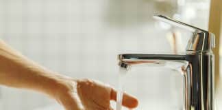 Man washing and cleaning her hand in bathroom, soft focus. Closeup of fingers under flowing tap water. Hygiene, bedtime procedures