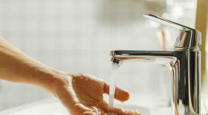 Man washing and cleaning her hand in bathroom, soft focus. Closeup of fingers under flowing tap water. Hygiene, bedtime procedures