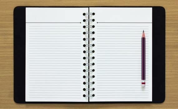 Blank spiral notebook and pencil on wood background