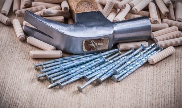Woodworking dowels nails claw hammer on wooden background.