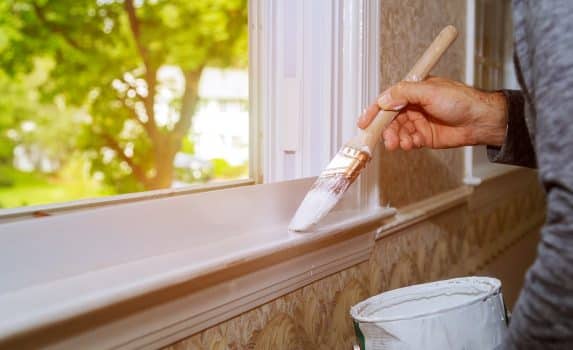 Male hands repairs painting window trim at home closeup