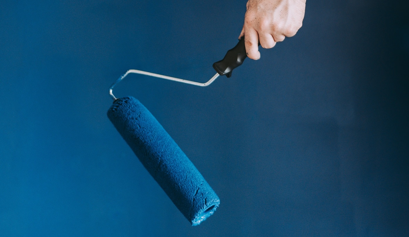 A closeup shot of a female using paint rollers with the color blue