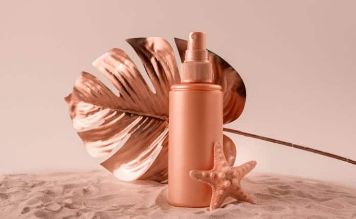 Sunscreen cream or lotion bottle with tropical monstera leaf colored in rose gold. Healthcare while vacationing concept.