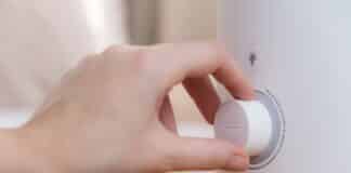 Woman turns on the modern air humidifier, aroma oil diffuser at home. Improving the comfort of living in a house, Improving the well-being. Ultrasonic steam technology
