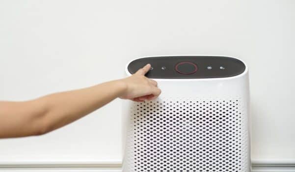 Woman is turning on air purifier in home
