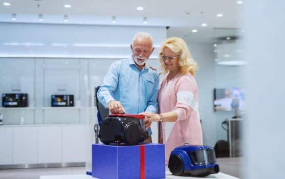 Cute caucasian senior couple choosing new vacuum cleaner for their home. Tech store interior.