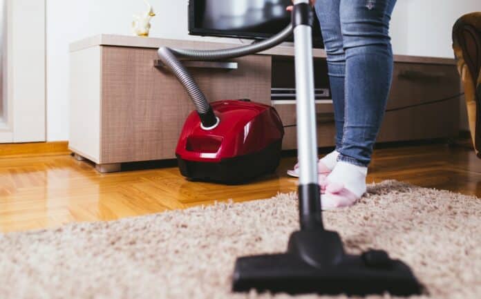 Young woman cleaning house with vacuum cleaner.
