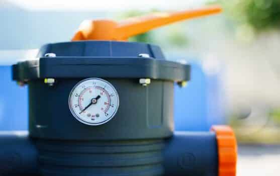 Pressure gauge measuring water pressure in a sand pump of an outdoor pool filtration system. High quality photo