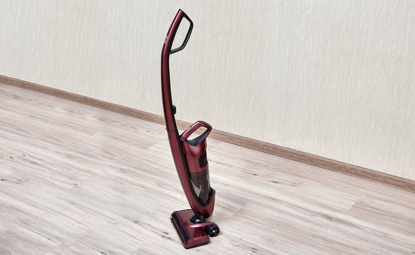 Handheld vacuum cleaner with a separate small dust tank in an empty room.