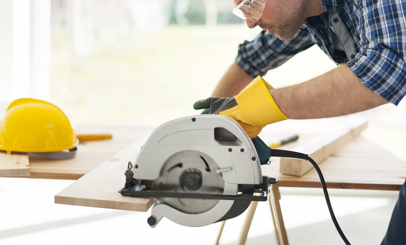 Male carpenter sawing wooden boards