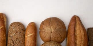 top view of different types of bread as baguette cob rye on white background with copy space