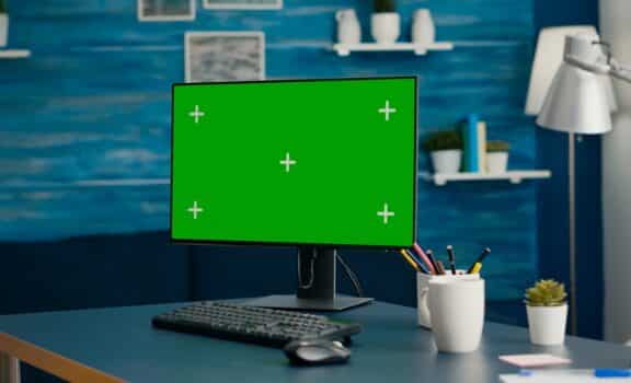 Close up of professional powerful computer with mock up green screen chroma key standing on table in bright living room with nobody in it. Pc with isolated display is ready for online business