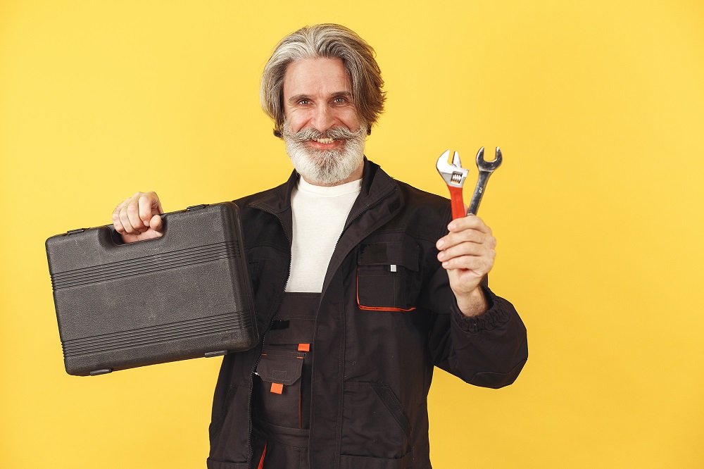 Guy with tool bag two wrenches on yellow background