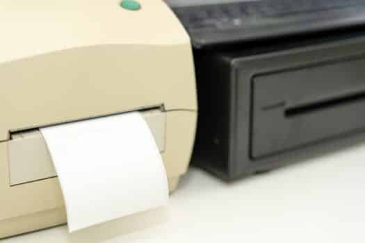 Label sticker printer with paper retail beside cash drawer on business shop counter in technology concept