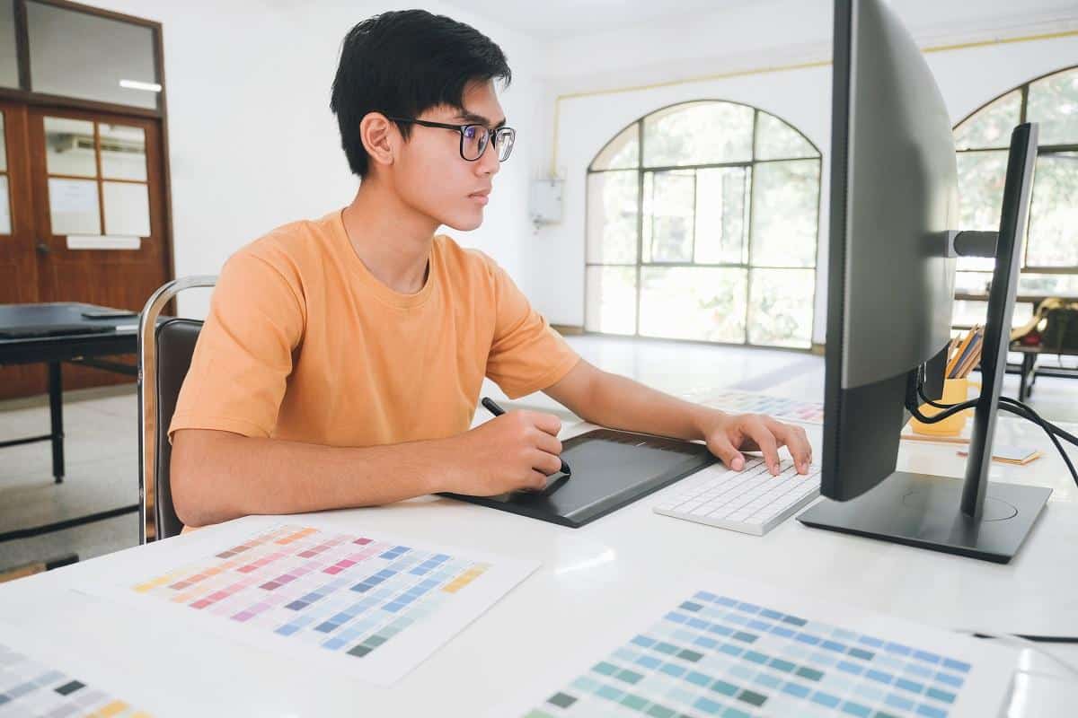 Graphic designer working with color samples for selection. Graphic designer at work. Color swatch samples. Young photographer and graphic designer at work in office.