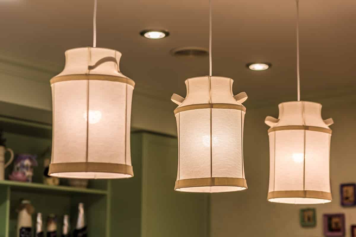 Closeup of decorative pendant lamps made of fabric in shape of milk cans hanging in home kitchen interior. Lighting design ideas. Fabric light fixtures.
