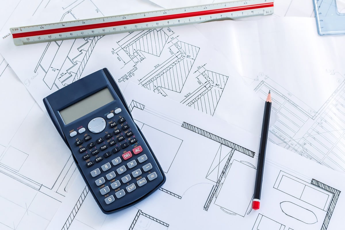 A top view of a scientific calculator on construction blueprints and tools for sketches. Scientific calculator for trigonometry buying guide.