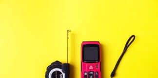 Laser rangefinder and measuring tape on yellow background. The measuring devices concept. How To Measure Distance Using Laser.