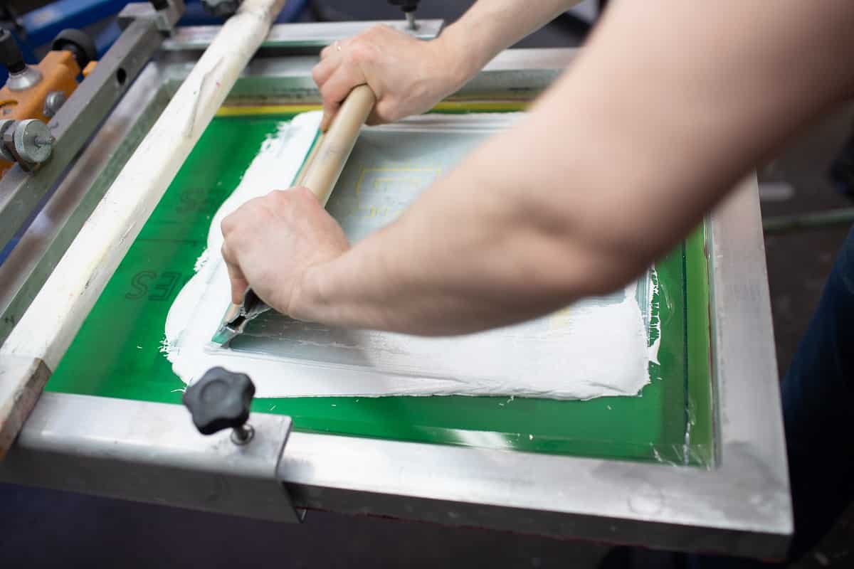 Serigraphy silk screen print process at clothes factory. Frame, squeegee and plastisol color paints. Screen printing vs heat press final words.