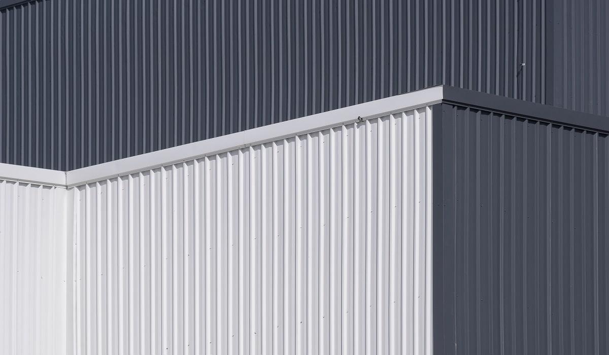 Low angle and side view of gray and white corrugated metal factory building wall in perspective view. Aluminum metal siding.
