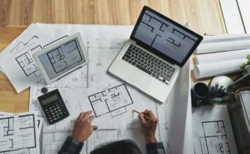 Professional architect making corrections in apartment blueprint, view from above. Do You Need A Specific Laptop For Architecture.