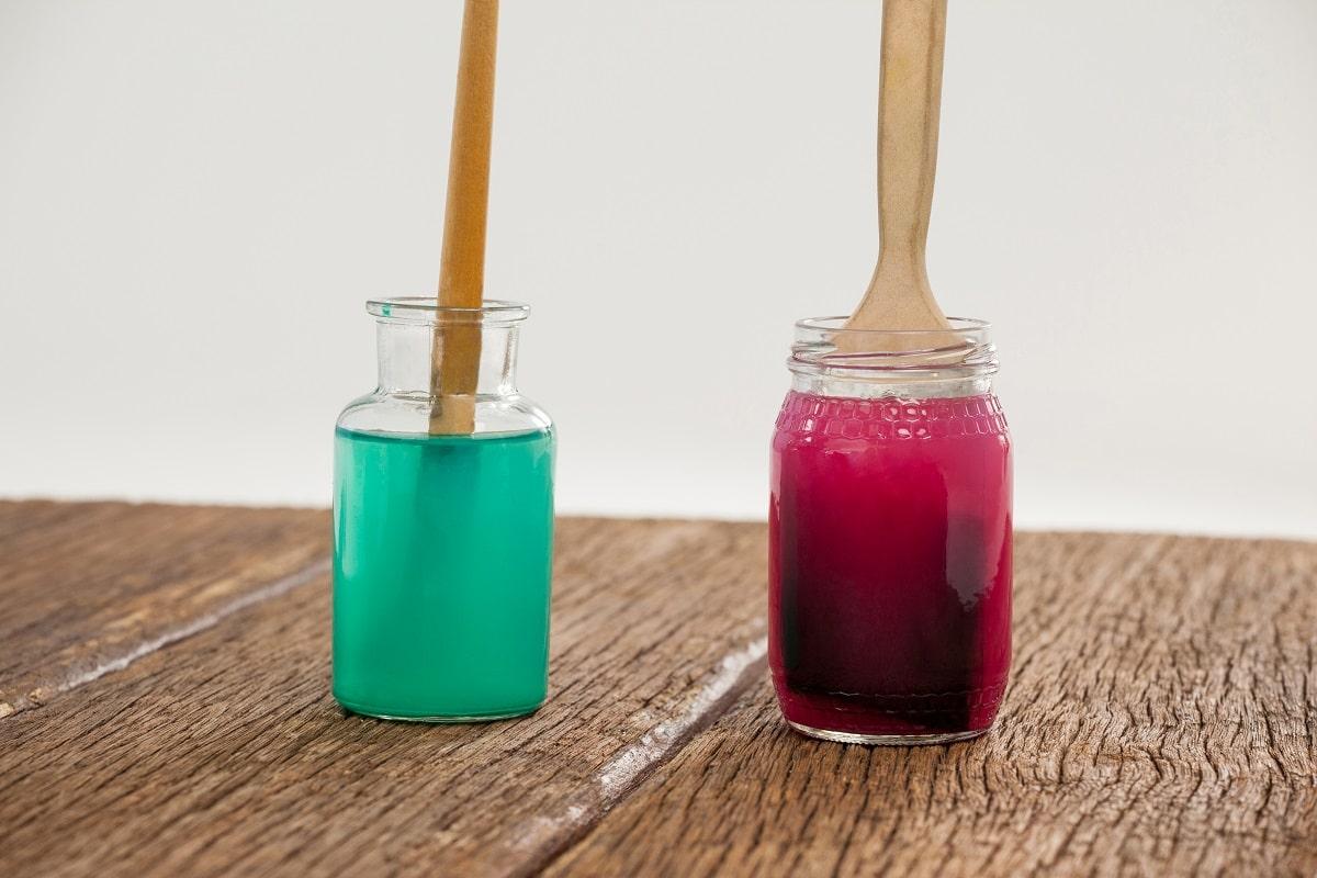 Paint brushes with blue and red paint dipped into water. Different ways to clean acrylic paint brushes.
